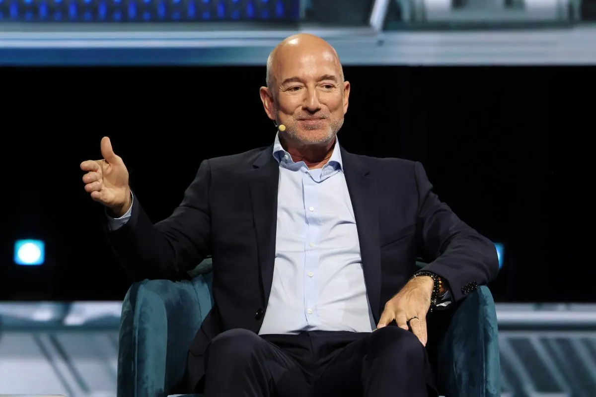 Jeff Bezos, Amazon founder, in a blue suit and light shirt, speaking at a business event